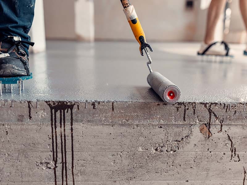 Construction worker apply epoxy resin on floor with paint roller
